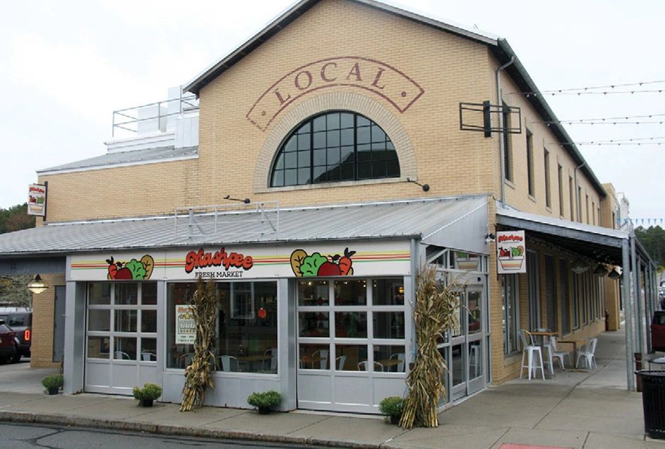 Exterior of a local fresh market in a brick building with large windows.